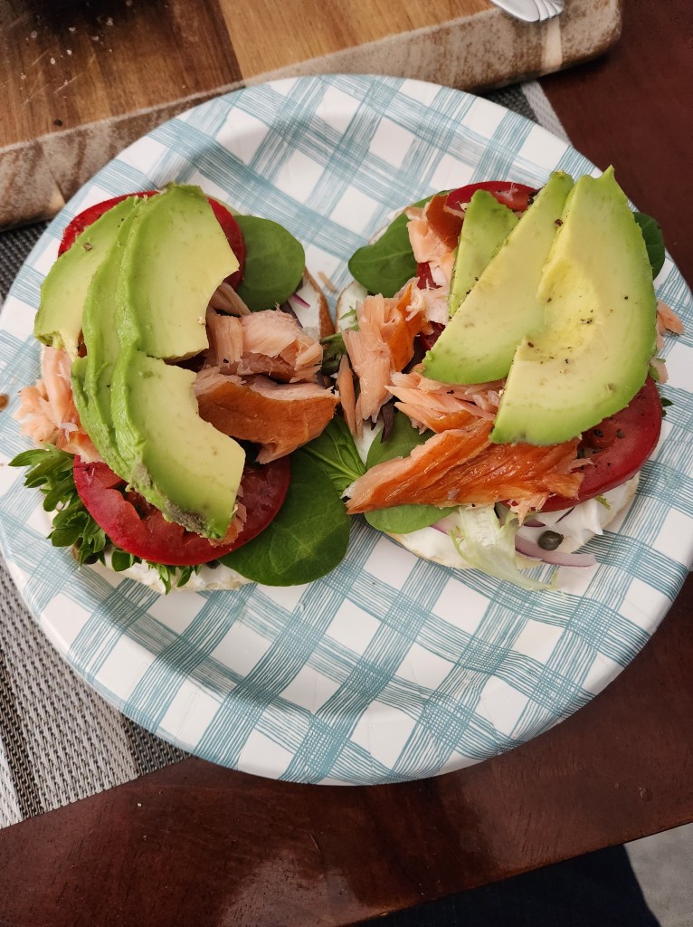 Breakfast bagel topped with cream cheese, arugula, tomatoes, smoked salmon, and avocado.